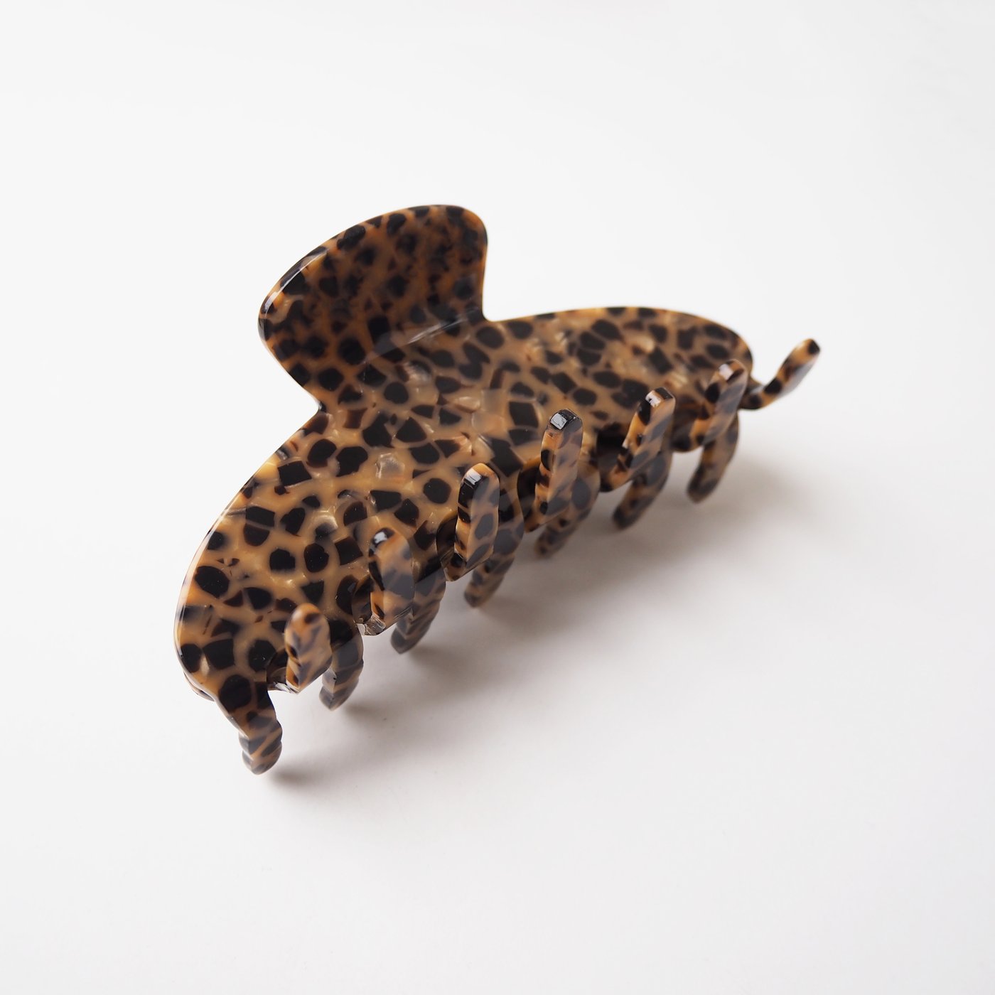 A brown hair clip with black flecks on a white background