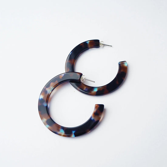 Tortoiseshell hoop earrings on a light grey background