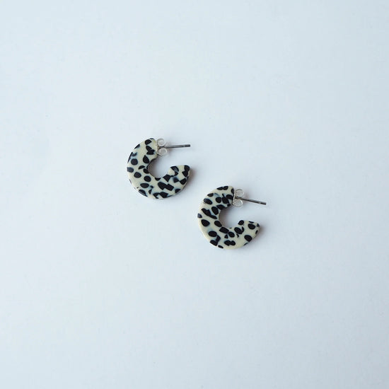 Pair of terrazzo cream and black hoop earrings on a light grey background