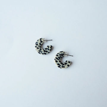 Pair of terrazzo cream and black hoop earrings on a light grey background