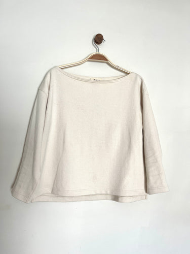 Ecru cotton jersey smock top with a boat neckline and long sleeves on a grey background