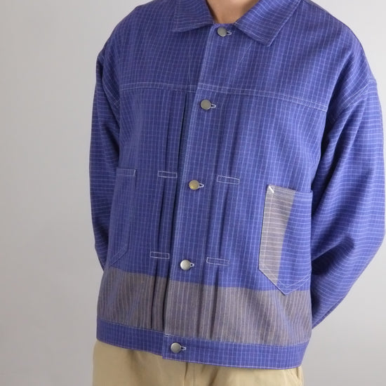 Man wearing a blue checkered shirt with a gray patch on a gray background