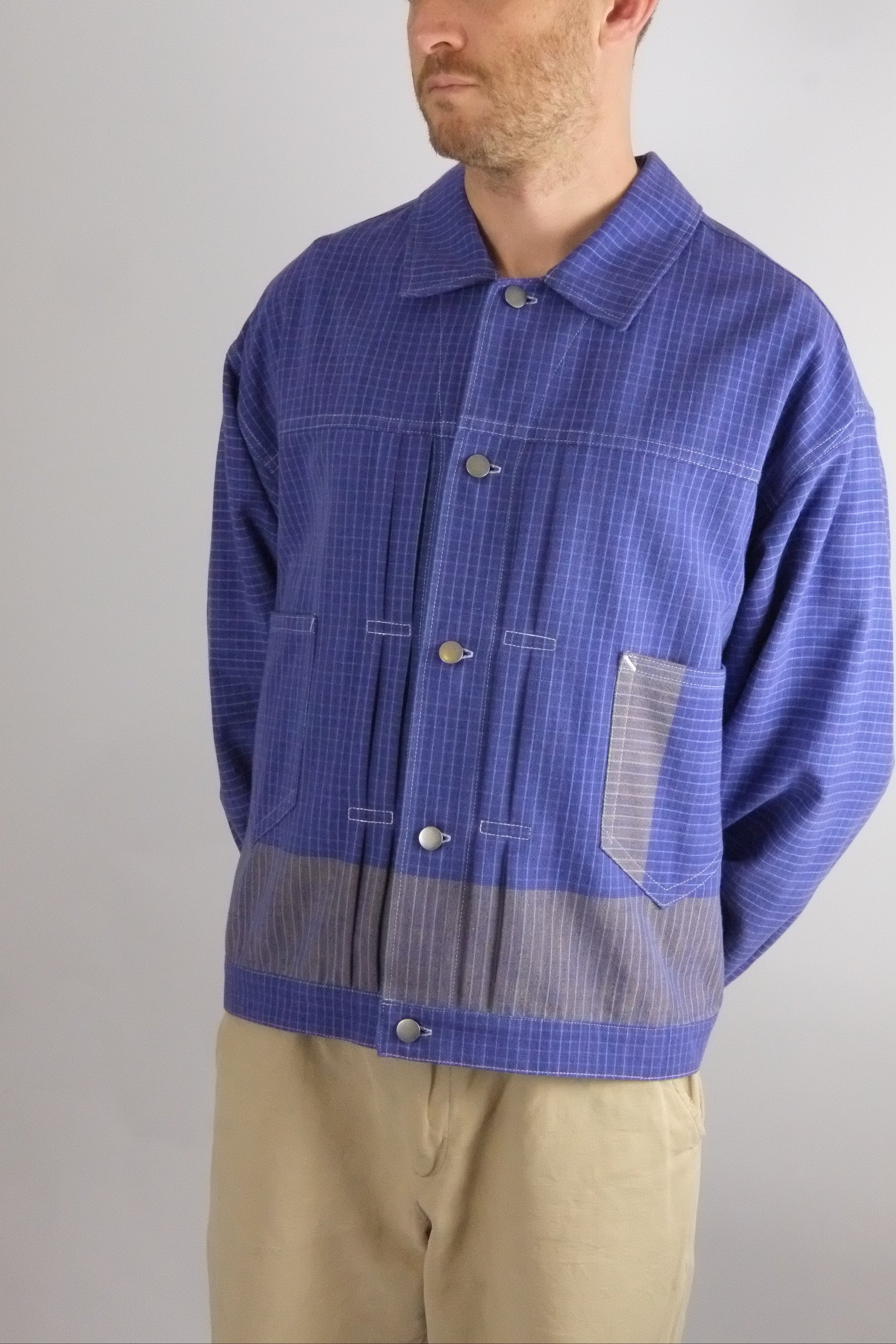 Man wearing a blue checkered shirt with a gray patch on a gray background
