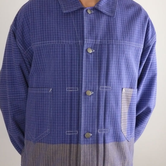 Person wearing a blue checkered shirt with a plain background