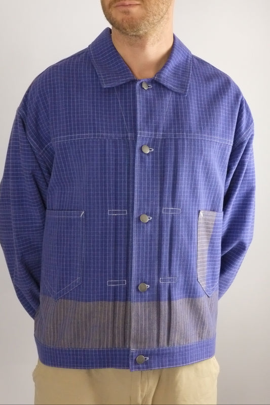 Person wearing a blue checkered shirt with a plain background