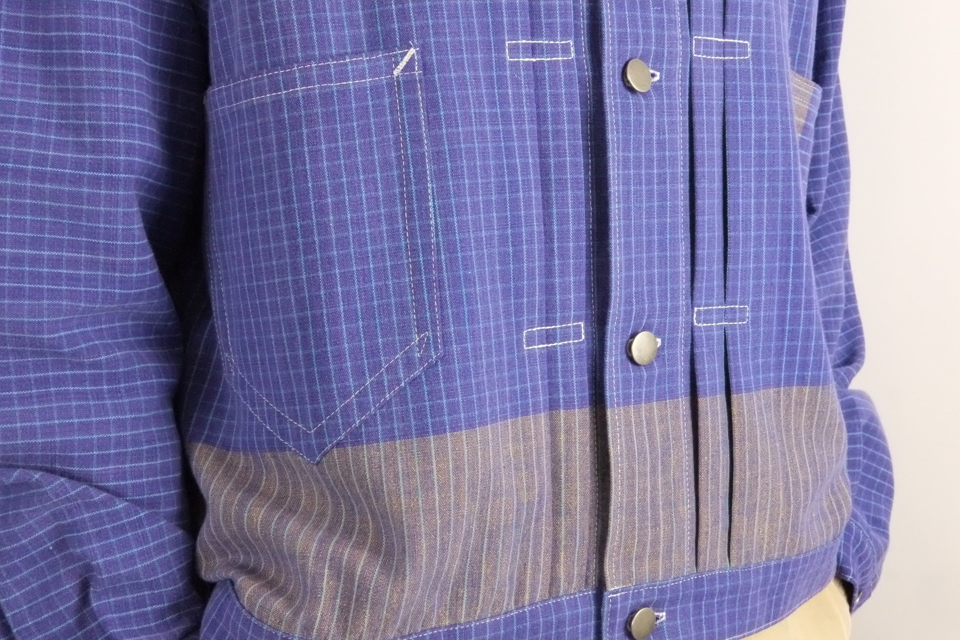 Close-up of a blue checkered shirt with a focus on the chest pocket and buttons.