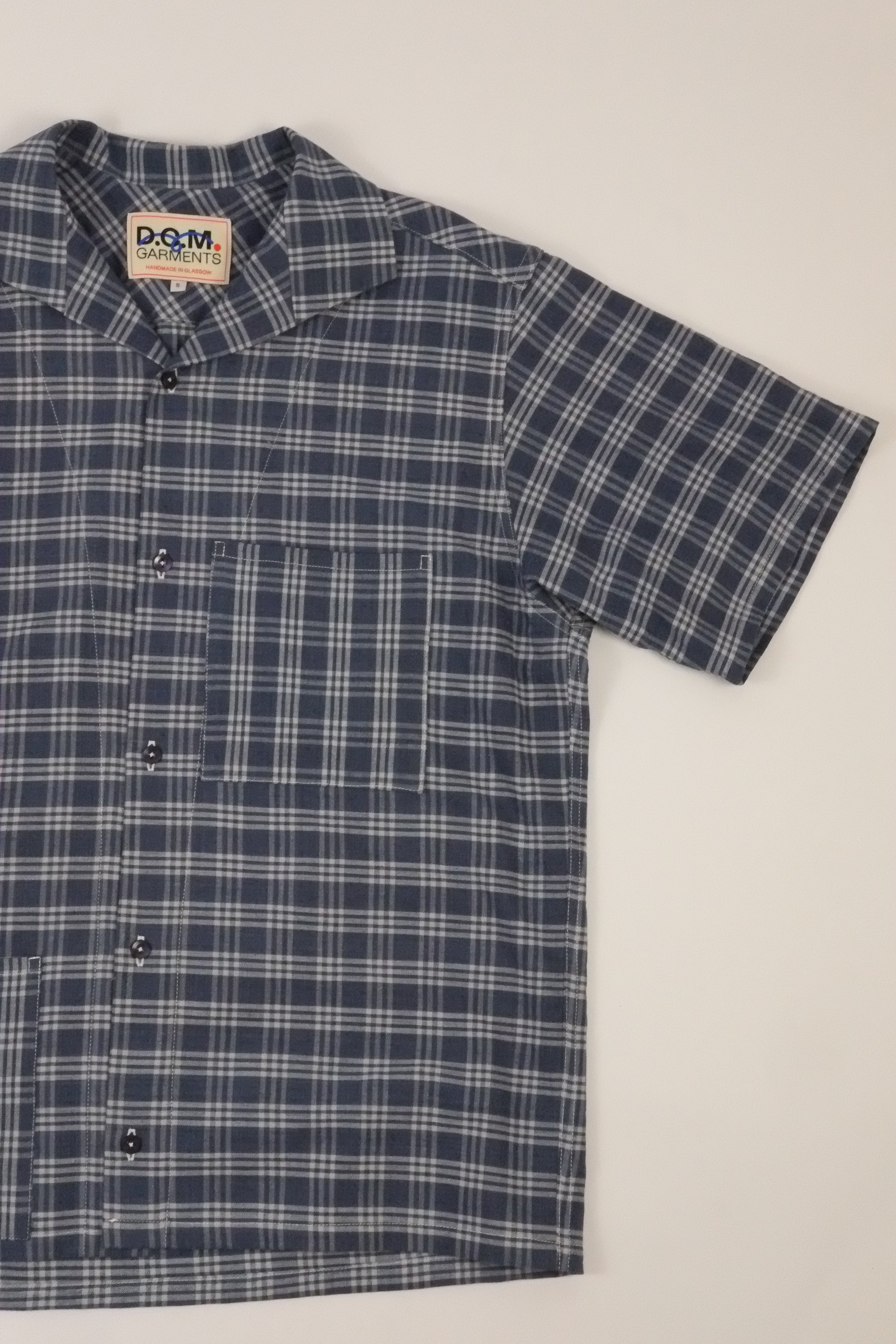 Blue and white plaid shirt with a brand label on a light gray background
