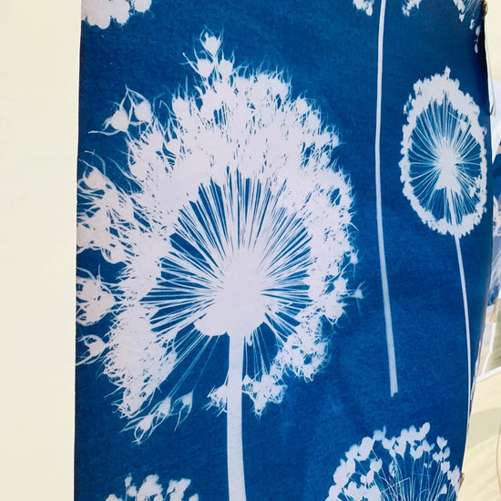White dandelion designs on a blue fabric background