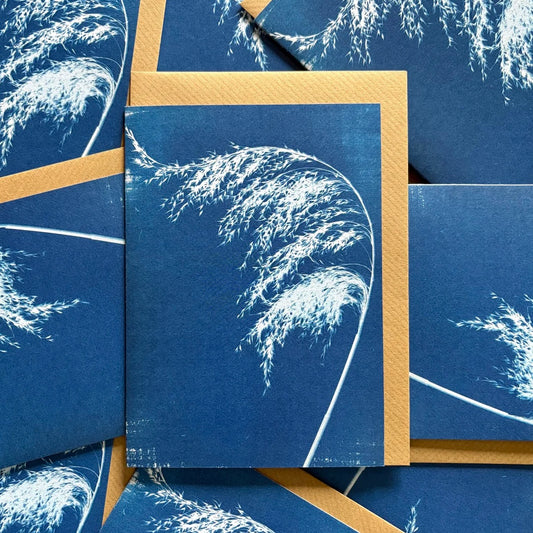 Multiple blue greeting cards with white floral designs and brown envelope behind