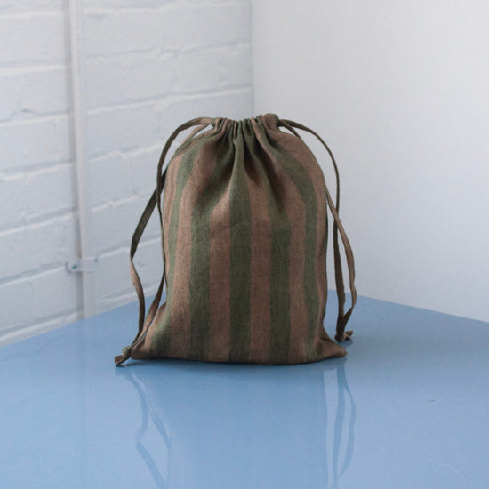A green striped bag on a blue table with a white background 