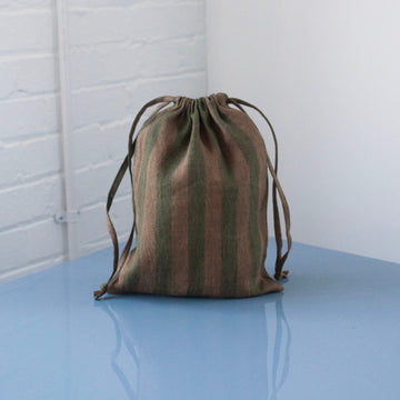 A green striped bag on a blue table with a white background 