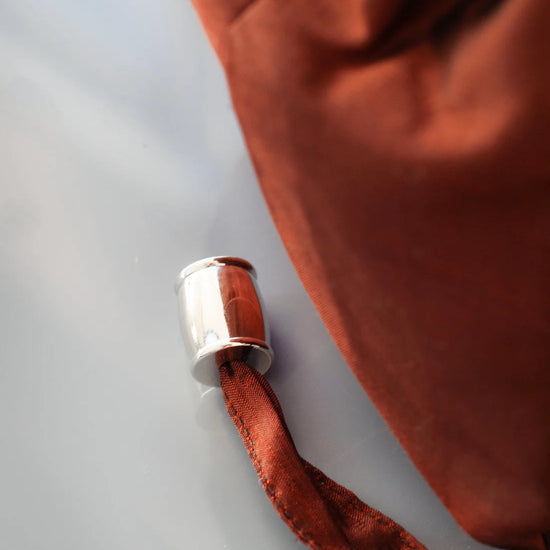Nickel toggle on brown silk bag on a grey background
