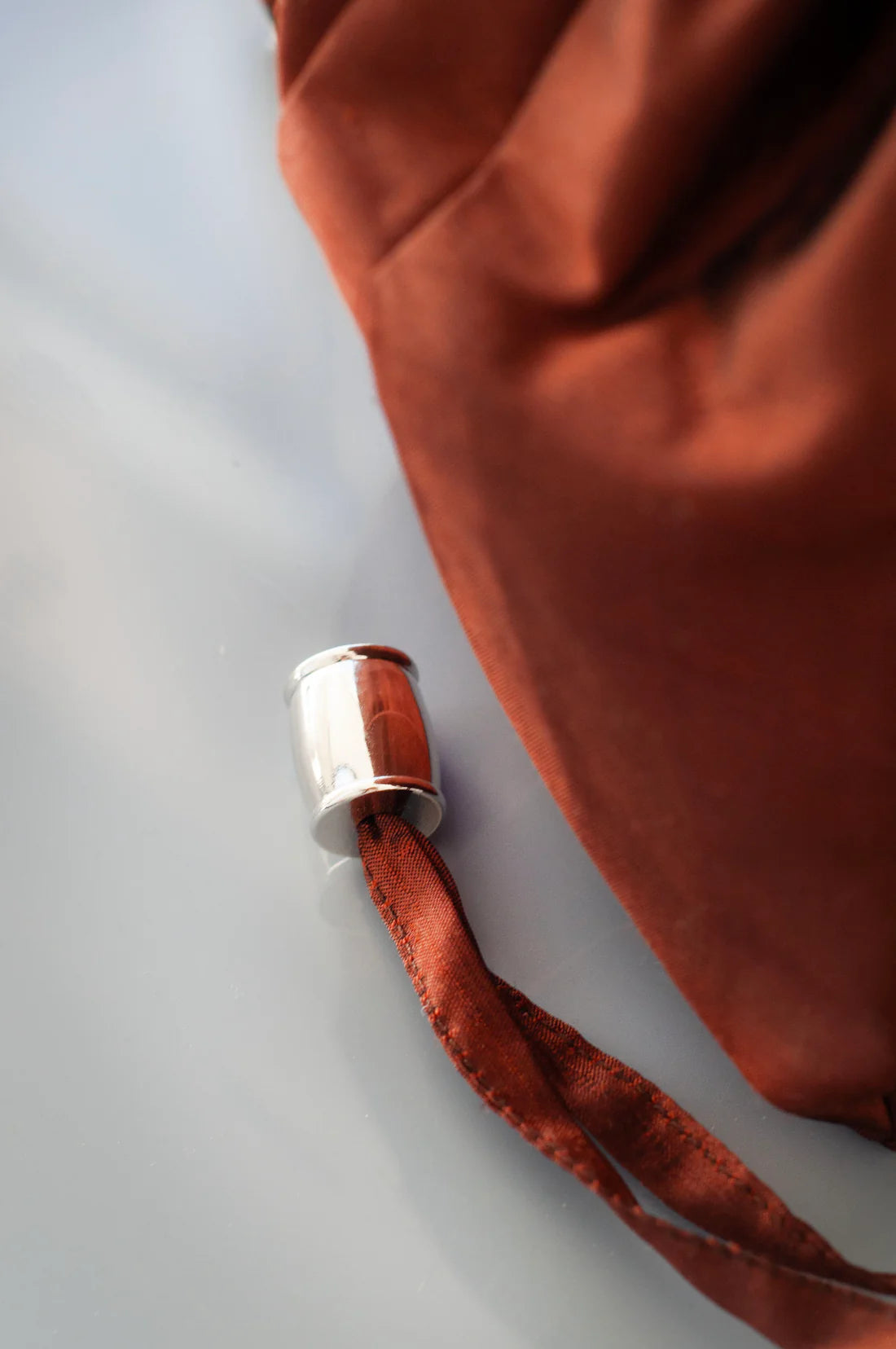 Nickel toggle on brown silk bag on a grey background