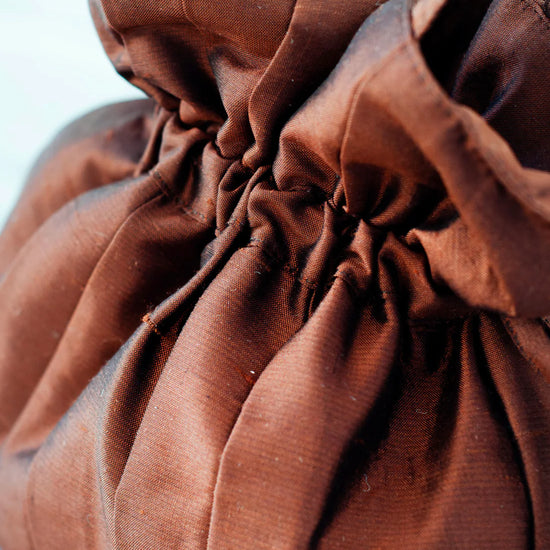 Close-up of a brown drawstring bag against a white and blue background