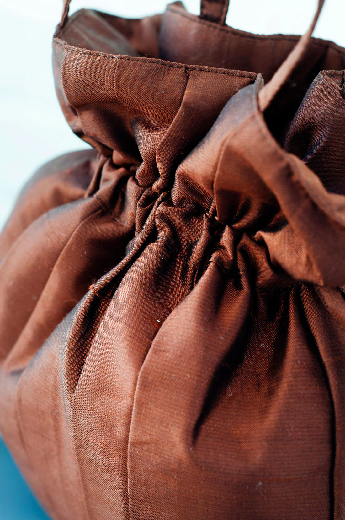 Close-up of a brown drawstring bag against a white and blue background