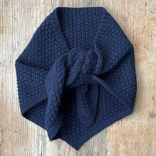 Load image into Gallery viewer, Navy knitted lambswool triangle neckerchief style scarf with texture on a pale wood background
