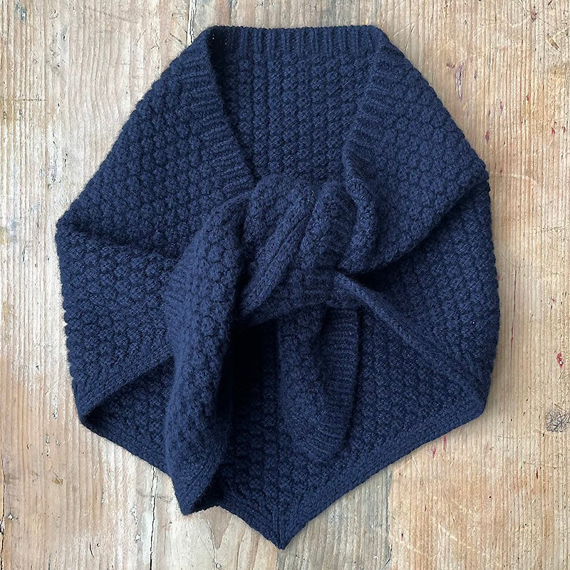 Navy knitted lambswool triangle neckerchief style scarf with texture on a pale wood background