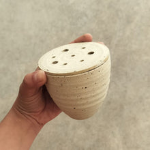 Load image into Gallery viewer, Hand holding a ceramic floral tumbler with a textured surface against a neutral background
