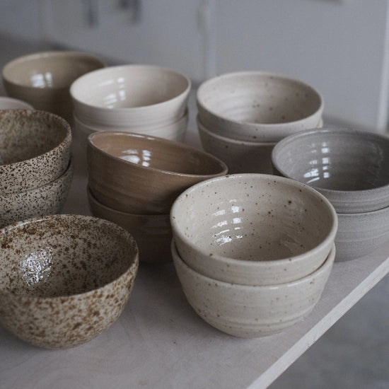 Collection of ceramic bowls on a concrete floor with a neutral background