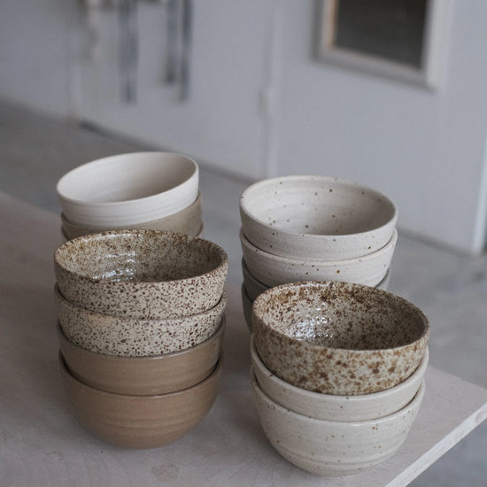 Set of ceramic bowls in various colors on a light surface.