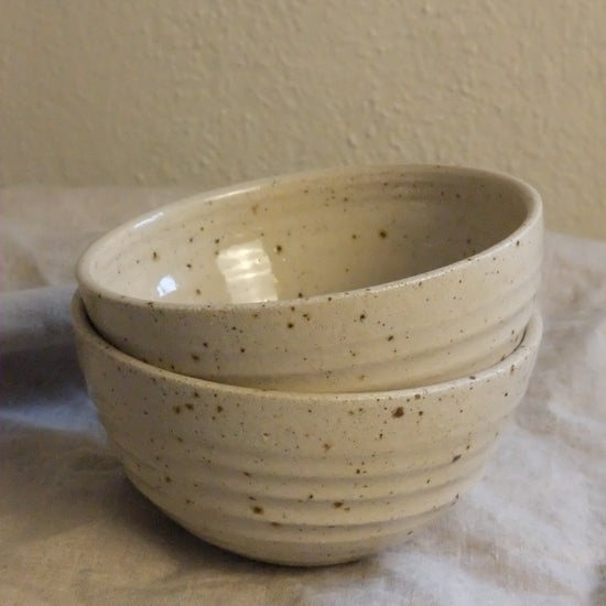 Speckled ceramic bowl held against a neutral background