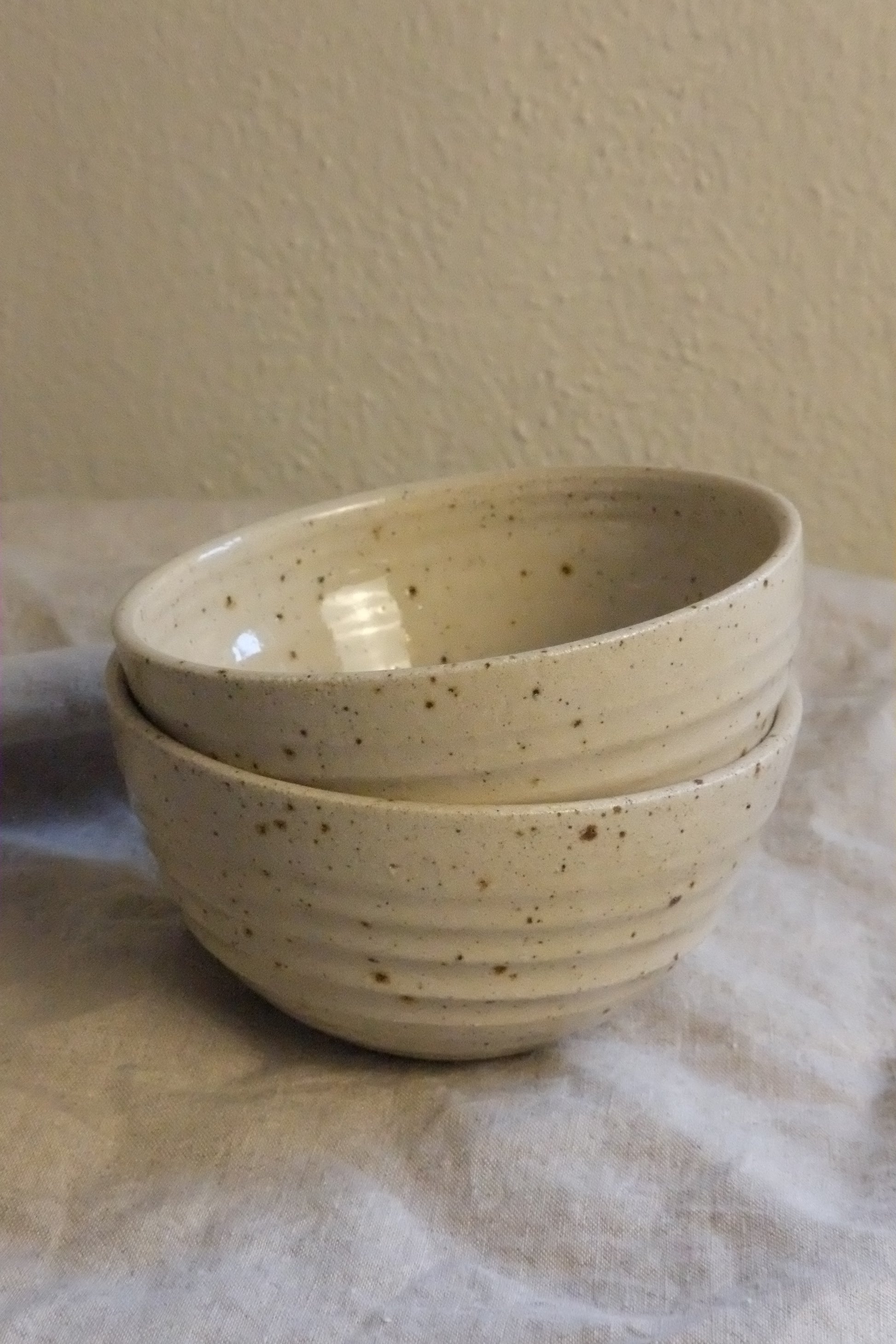 Speckled ceramic bowl held against a neutral background