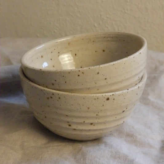 Speckled ceramic bowl held against a neutral background