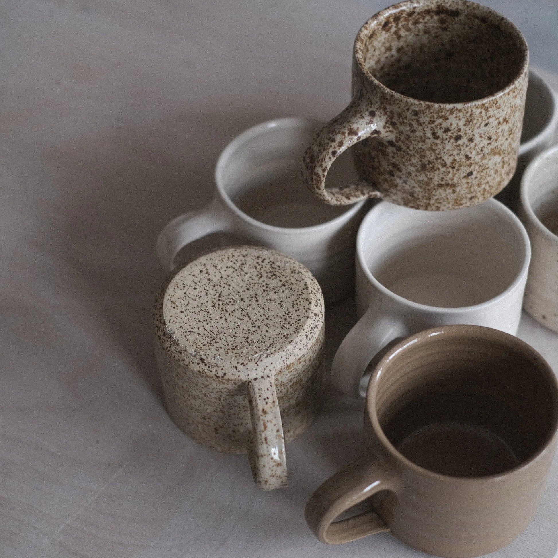 Set of ceramic mugs with speckled patterns on a light surface
