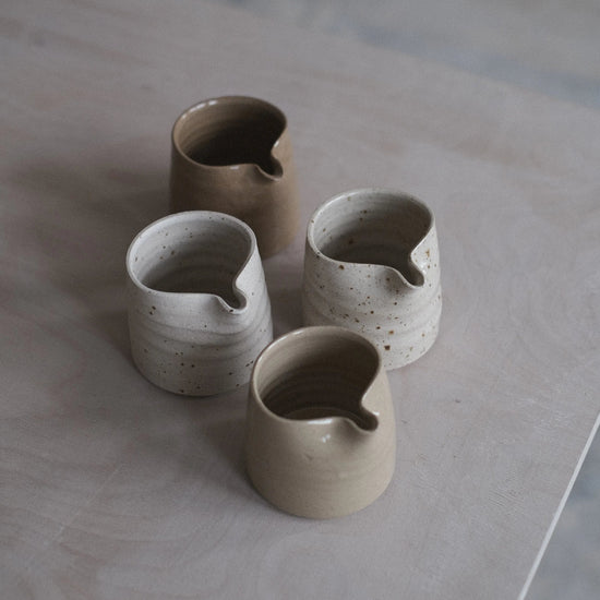 Set of four ceramic cups on a light wooden surface