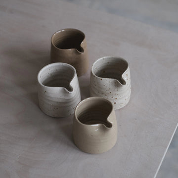 Set of four ceramic cups on a light wooden surface