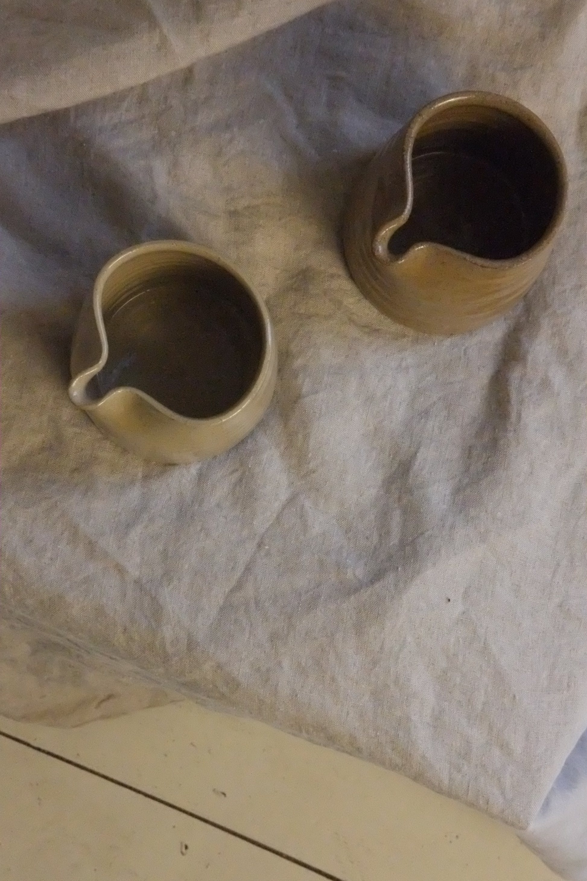 Two ceramic pitchers on a textured surface