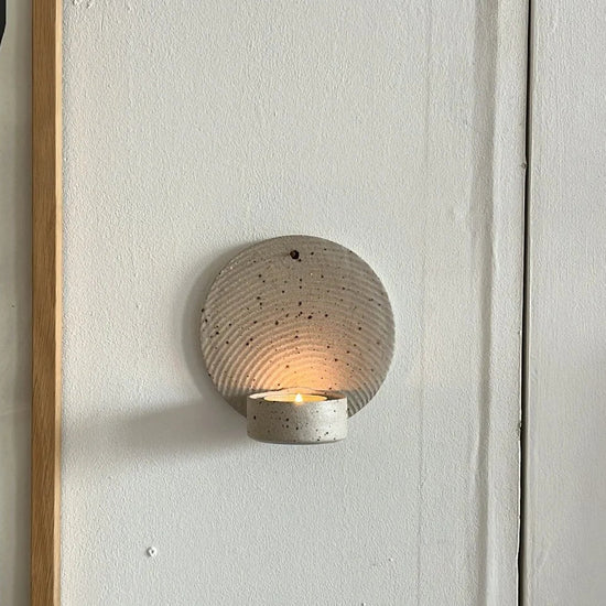 Framed abstract art on a wall with a round wall sconce below.