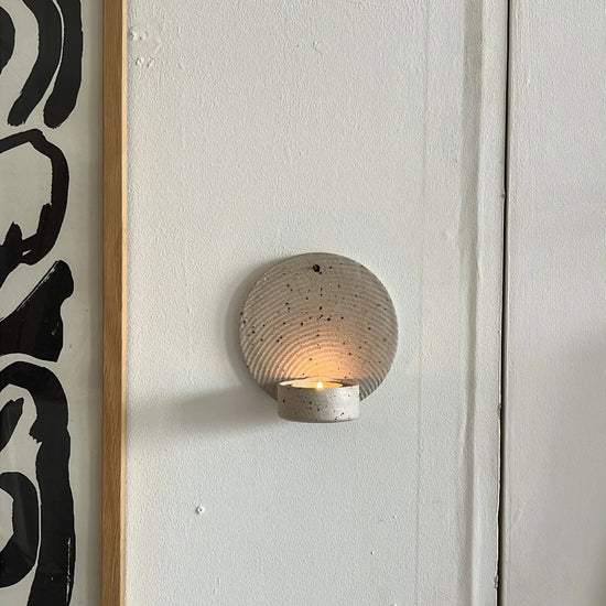 Framed abstract art on a wall with a round wall sconce below.