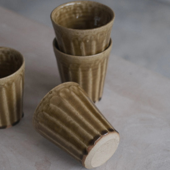 Three ceramic cups on a stone surface with a neutral background