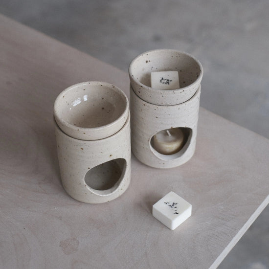 Two ceramic containers with a small block on a concrete surface