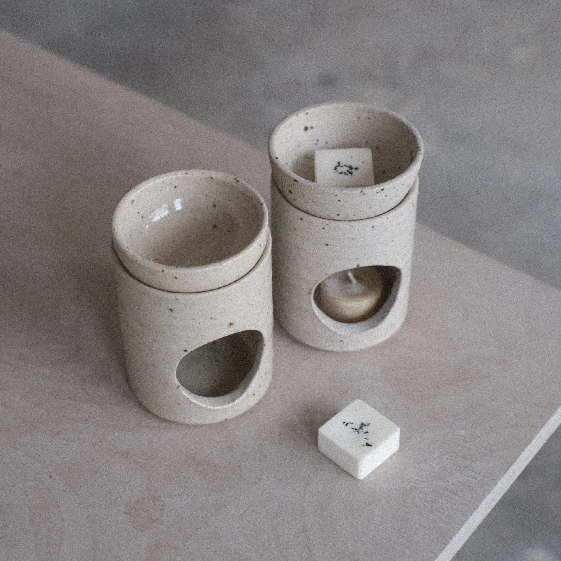 Two ceramic containers with a small block on a concrete surface