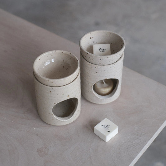 Two ceramic containers with a small block on a concrete surface