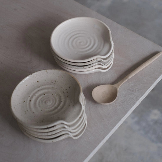 Stacked ceramic bowls with a wooden spoon on a gray surface