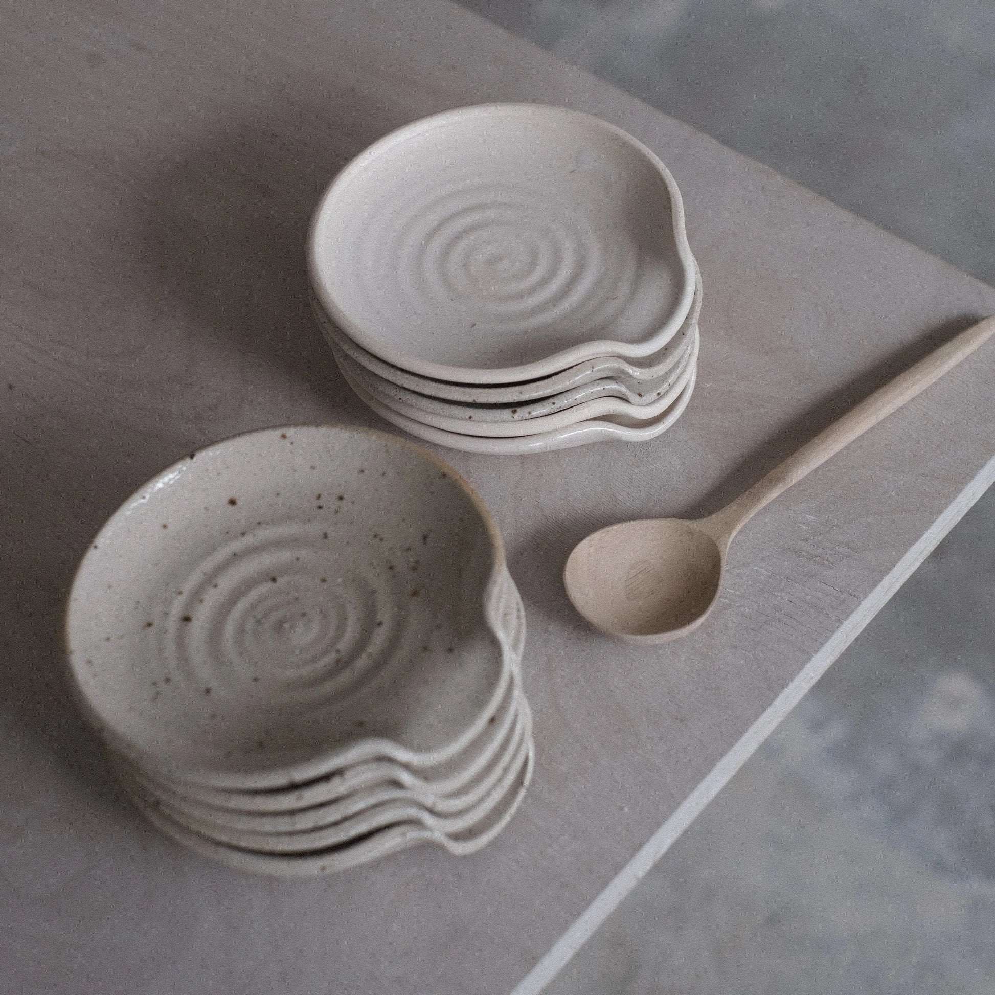 Stacked ceramic bowls with a wooden spoon on a gray surface
