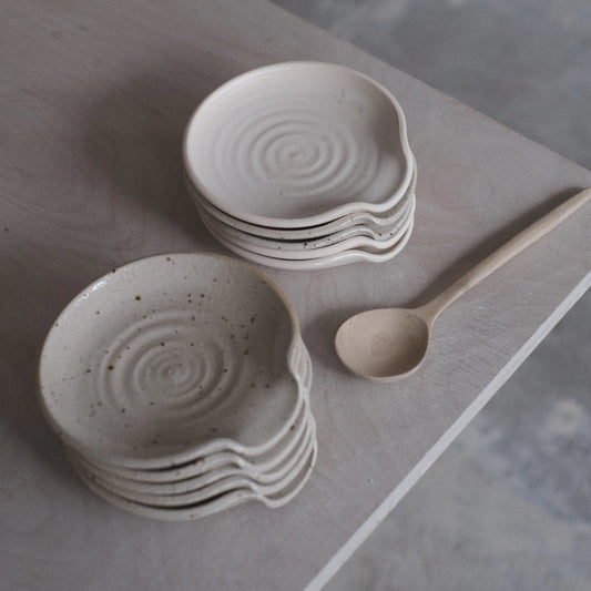 Stacked ceramic bowls with a wooden spoon on a gray surface