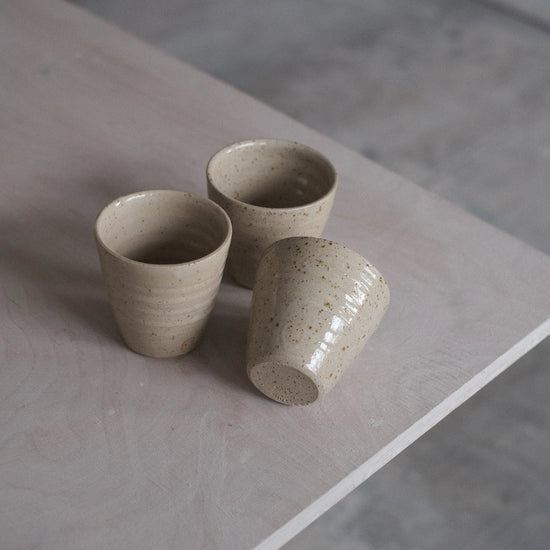 Three ceramic cups on a stone surface with a neutral background