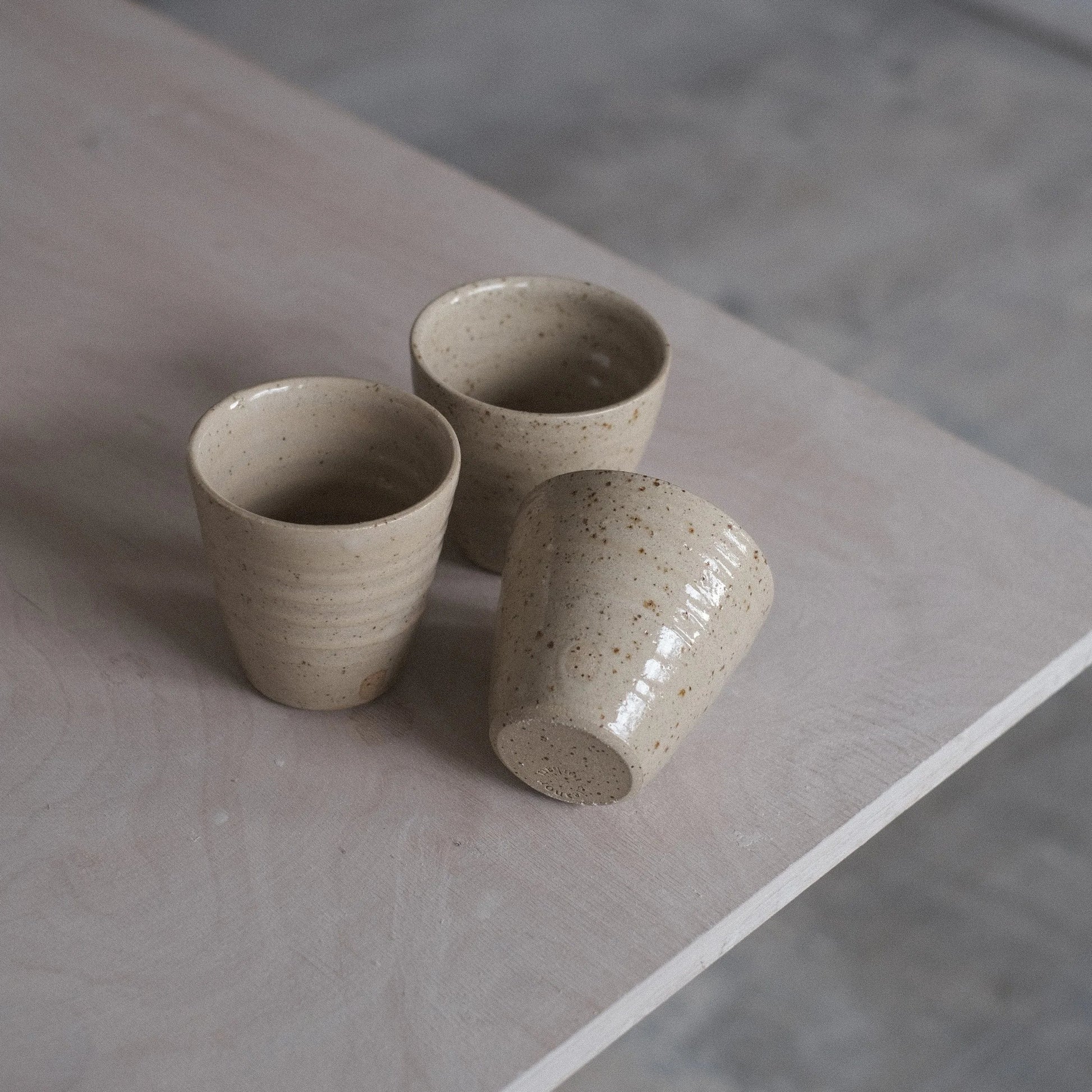 Three ceramic cups on a stone surface with a neutral background