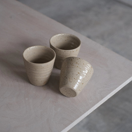 Three ceramic cups on a stone surface with a neutral background