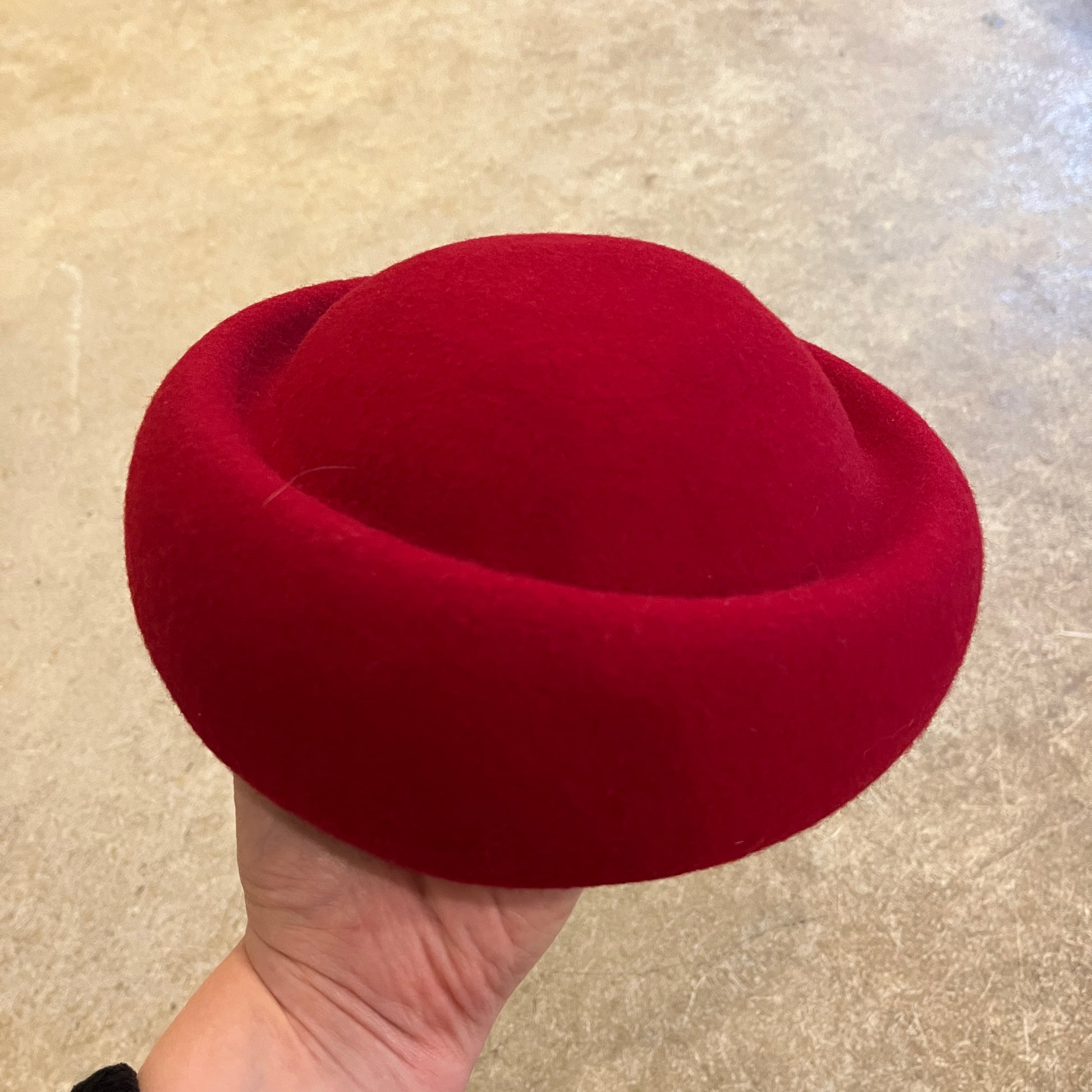 Red hat held by a hand on a neutral background