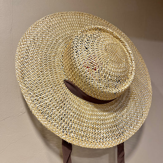 Woven straw hat on a stand against a neutral background