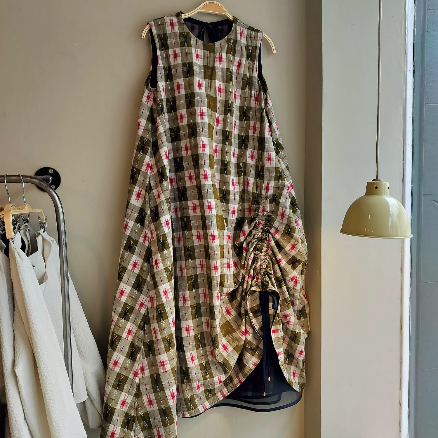 Plaid dress hanging on a rack with a neutral background