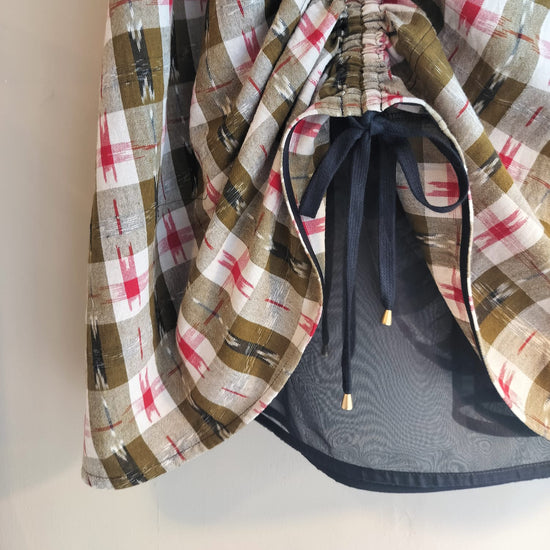 Plaid-patterned garment with a drawstring on a neutral background