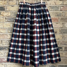 Load image into Gallery viewer, Ikat navy, brown and cream cotton checked midi skirt with an elastic waistband on a pale brick background
