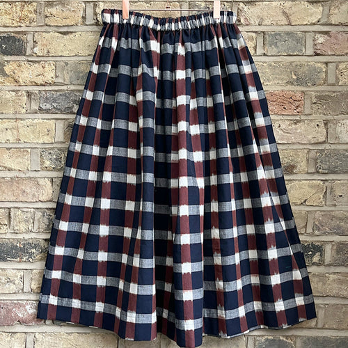 Ikat navy, brown and cream cotton checked midi skirt with an elastic waistband on a pale brick background