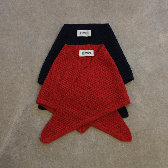 Two knitted scarves, one red and one navy , with 'ELWIN' labels on a beige surface.